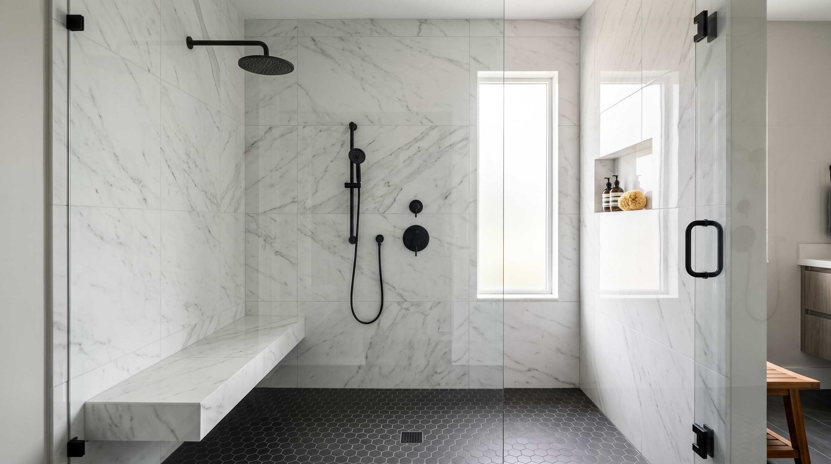 Luxury Florida shower interior fully tiled in large-format polished white marble-look porcelain with matte black trim and dark hex mosaic floor