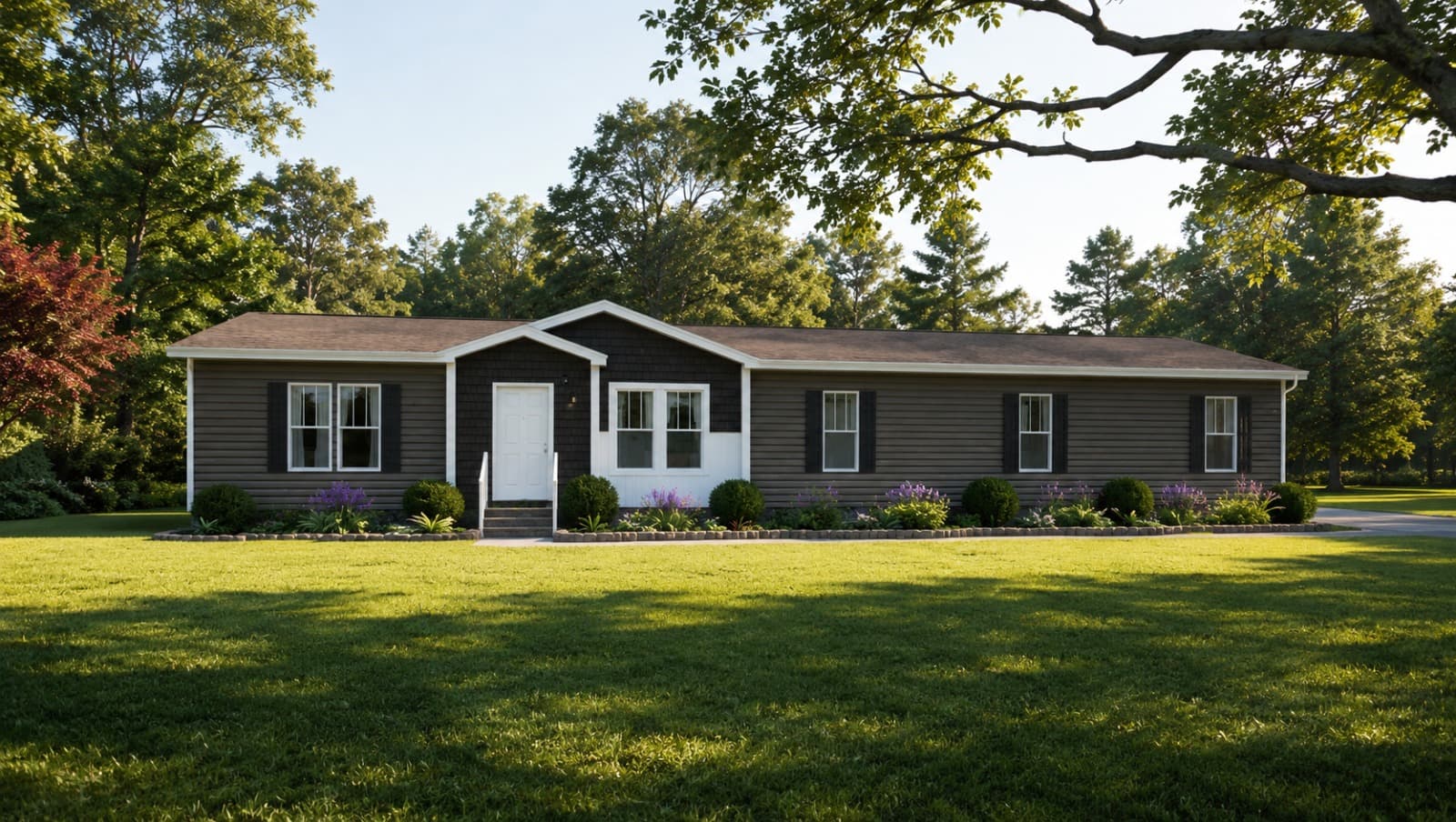 Brown clapboard exterior of a Lucky Ranch manufactured home — central gable entry porch, dark shutters, white front door, manicured front beds with lavender, mature oak canopy framing the view