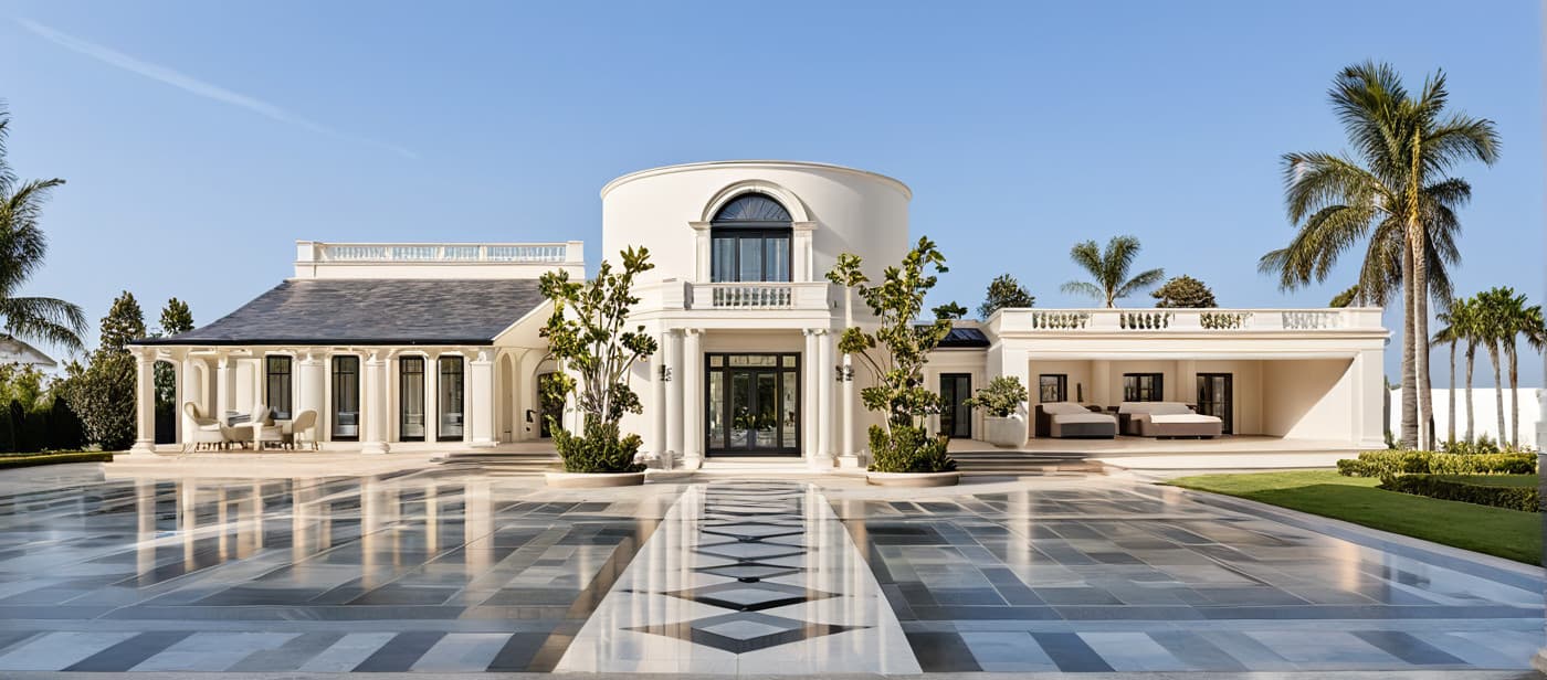 Architectural rendering of a finished Innova estate — a cream classical villa with central rotunda, columned loggias, and palm-lined patterned marble courtyard under a clear Florida sky